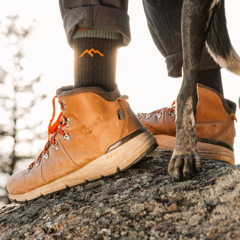 Person standing on a rock with a dog in Darn Tough Hiking socks and Danner Boots