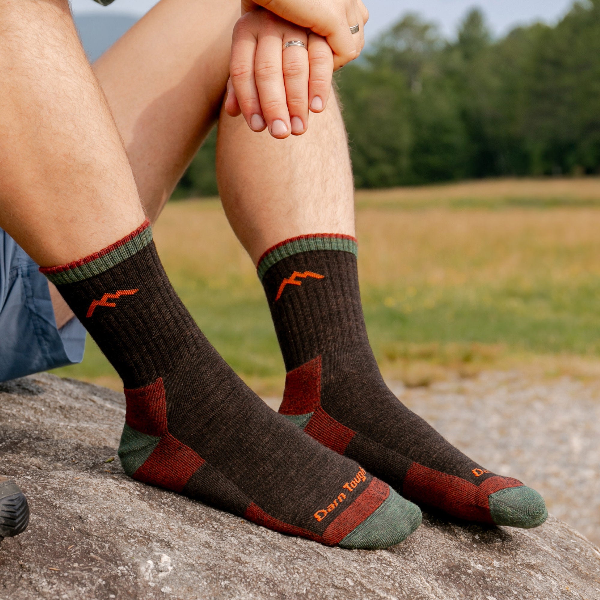 models legs up on a rock with feet in the 1466 micro crew walnut colorway with field in background
