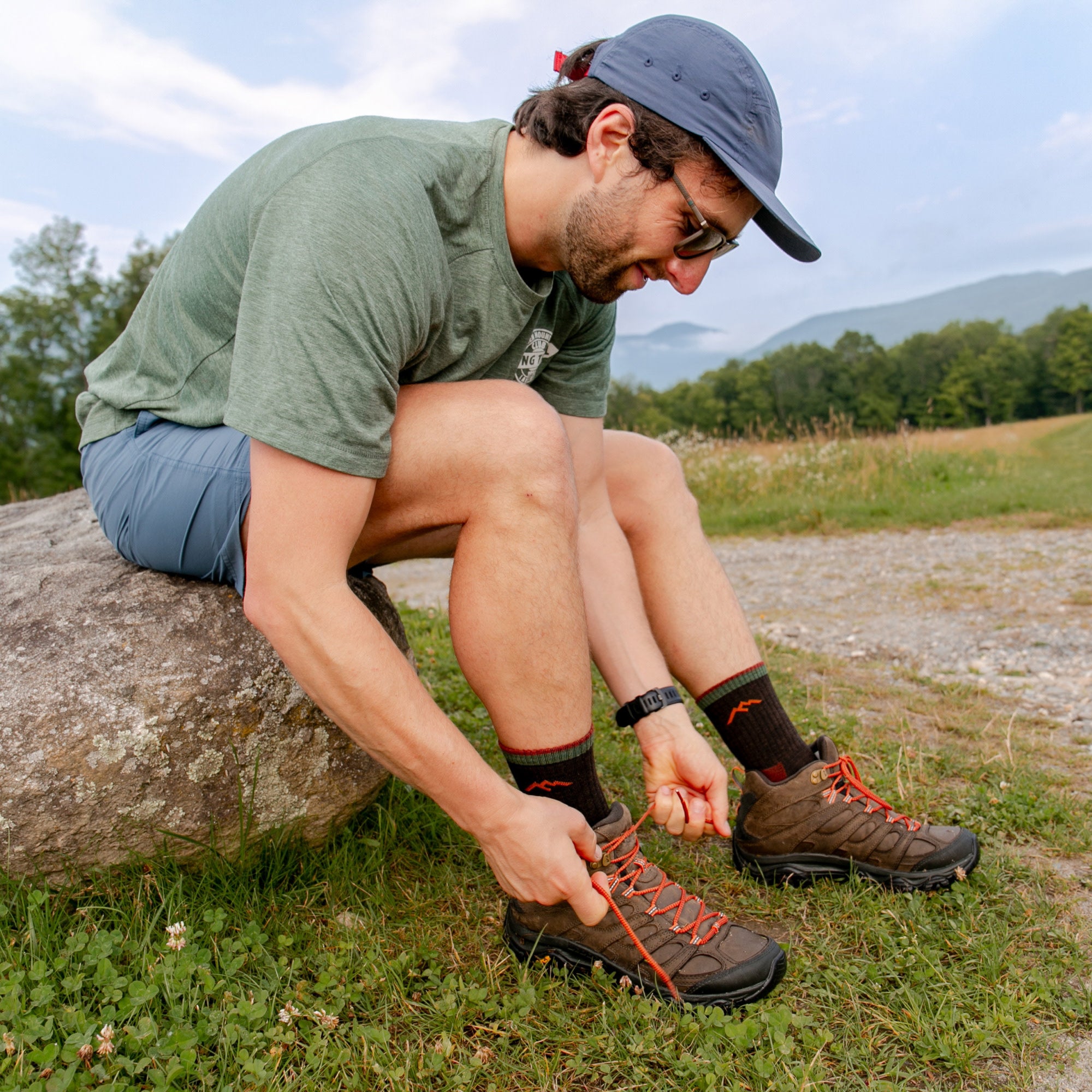 model sitting on a rock tying his shoes wearing the 1466 micro crew hiker in walnut colorway