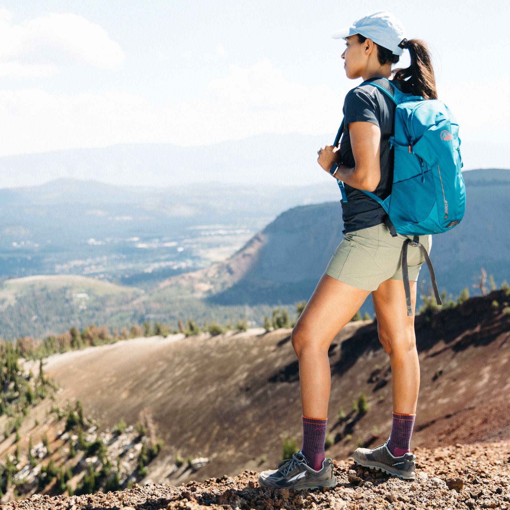 Woman standing looking out on the top of a mountain wearing the women's micro crew
 hiking sock in plum heather