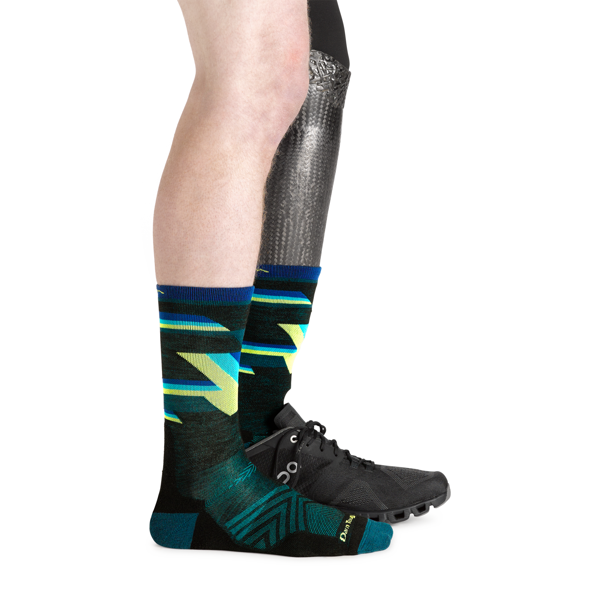 1056 men's bolt micro crew running socks in black on model with prosthetic leg wearing running shoe on left foot