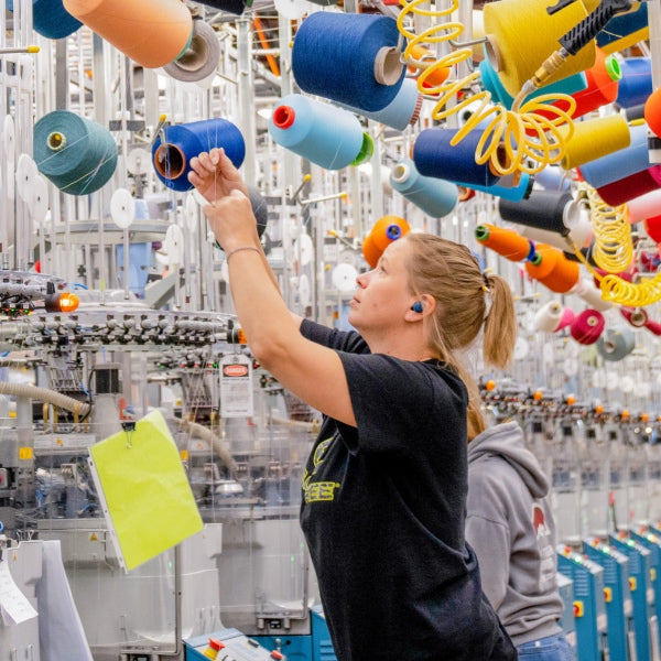 Visit Made in USA page - image of worker at Mill changing a cone of Merino yarn