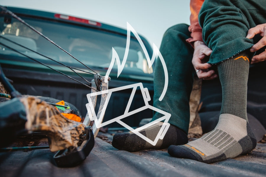Hunter in truck bed pulling on darn tough merino wool hunting socks for added warmth