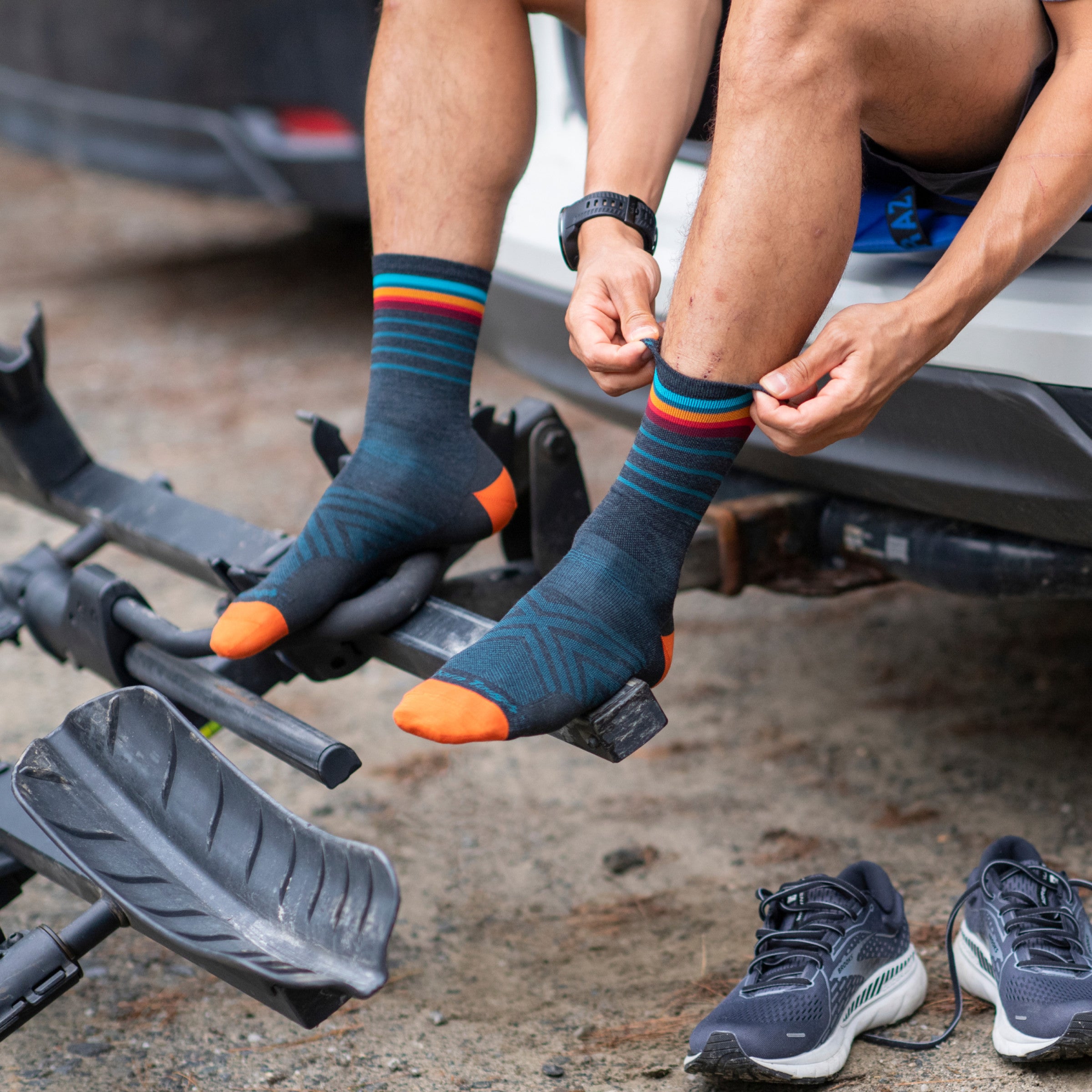 Trail runner seated on tailgate pulling on 1036 stride running socks