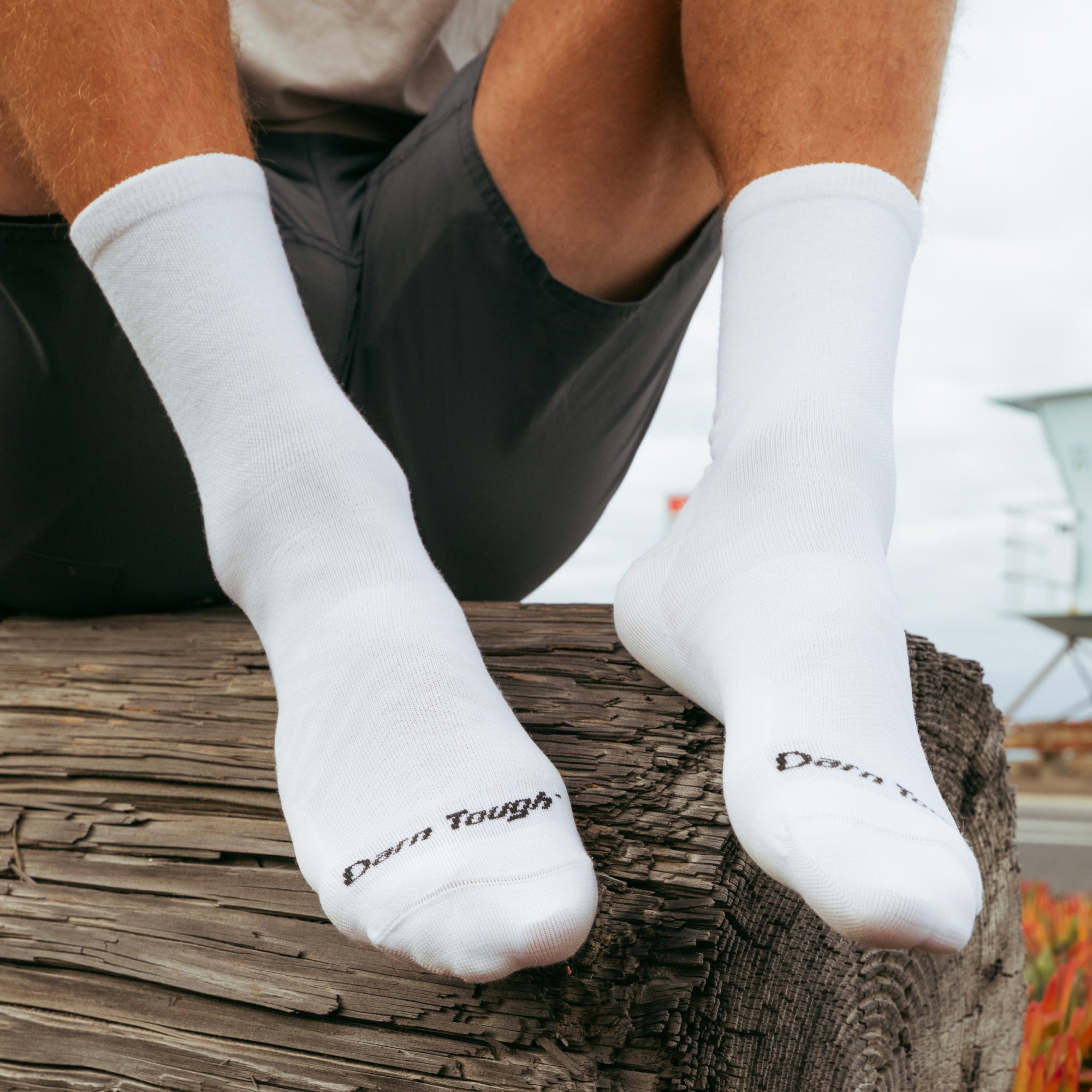 models feet up on a wood log wearing the 1035 men's micro crew running sock in white colorway
