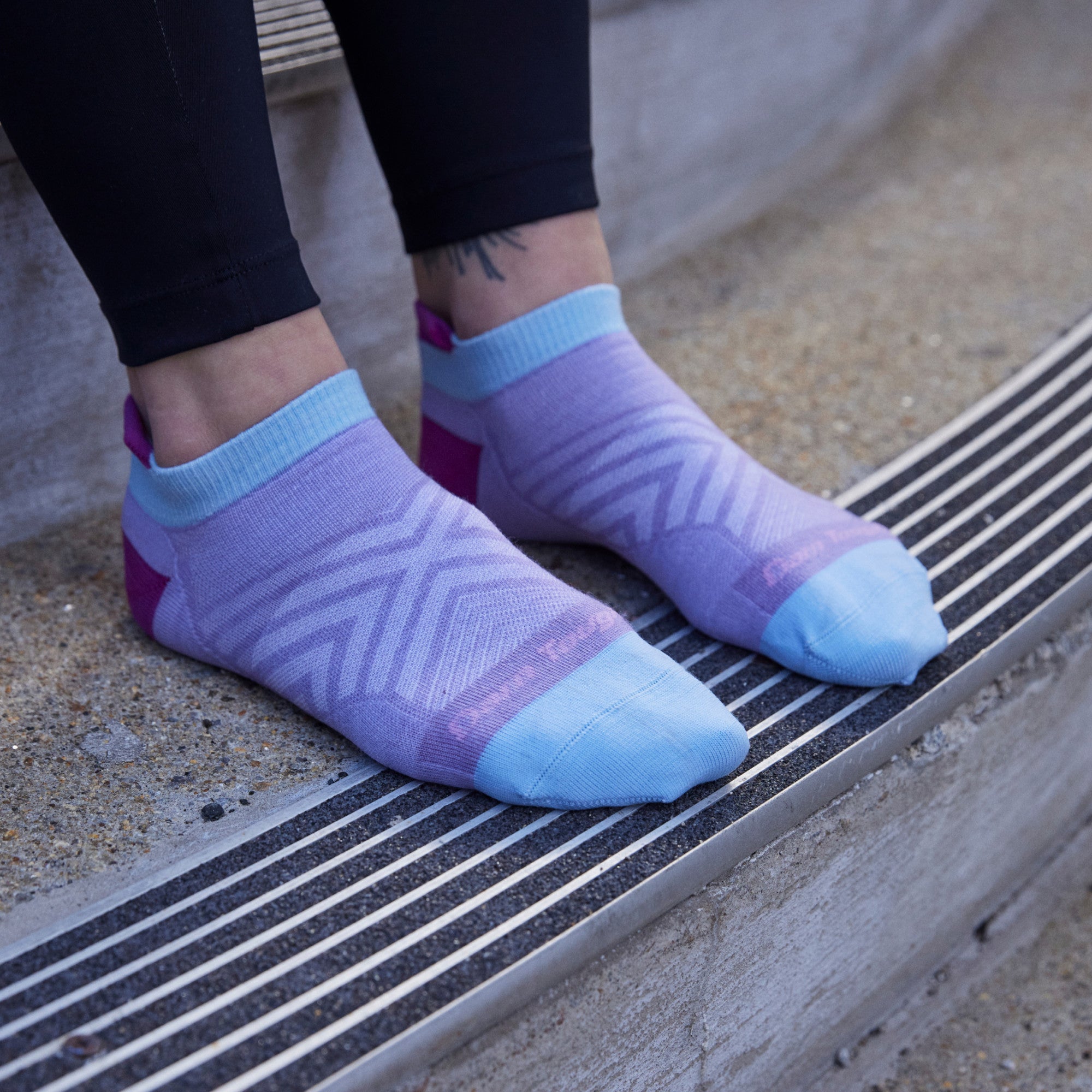 Close up shot of model sitting on concrete steps wearing 1043 socks in Lavender without shoes on