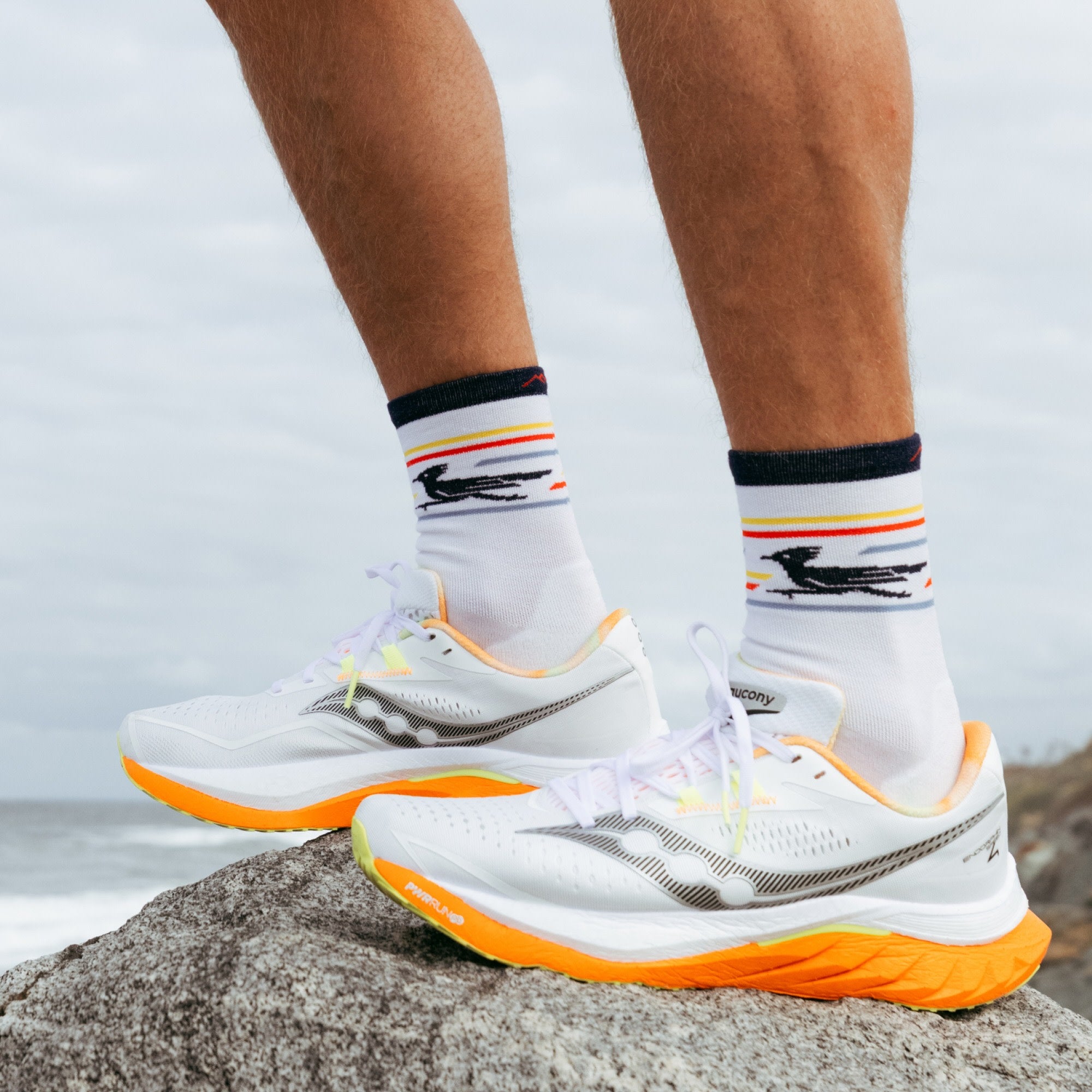 close up model feet in sneakers standing on rock wearing the 1062 front runner micro crew running sock in white colorway