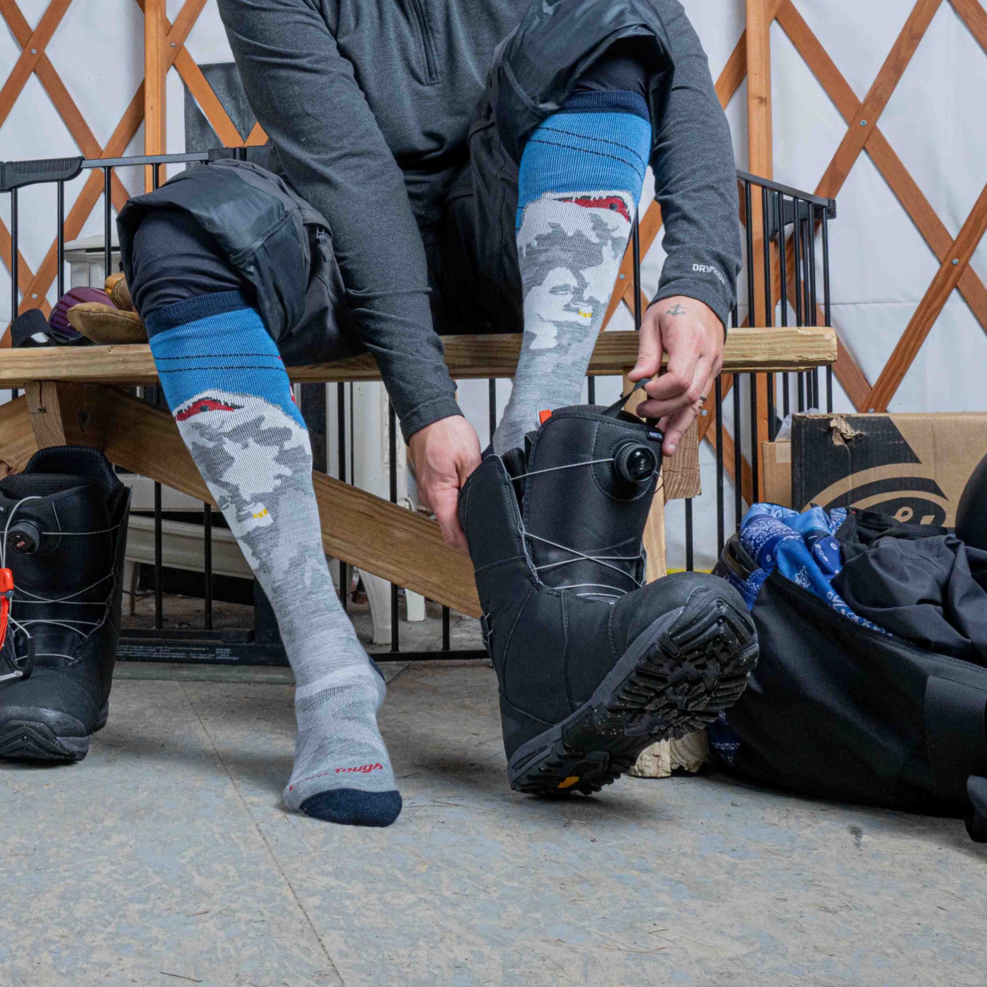 Model sitting on bench putting is snowboard boots on wearing the 8043 Heady Yeti in Gray