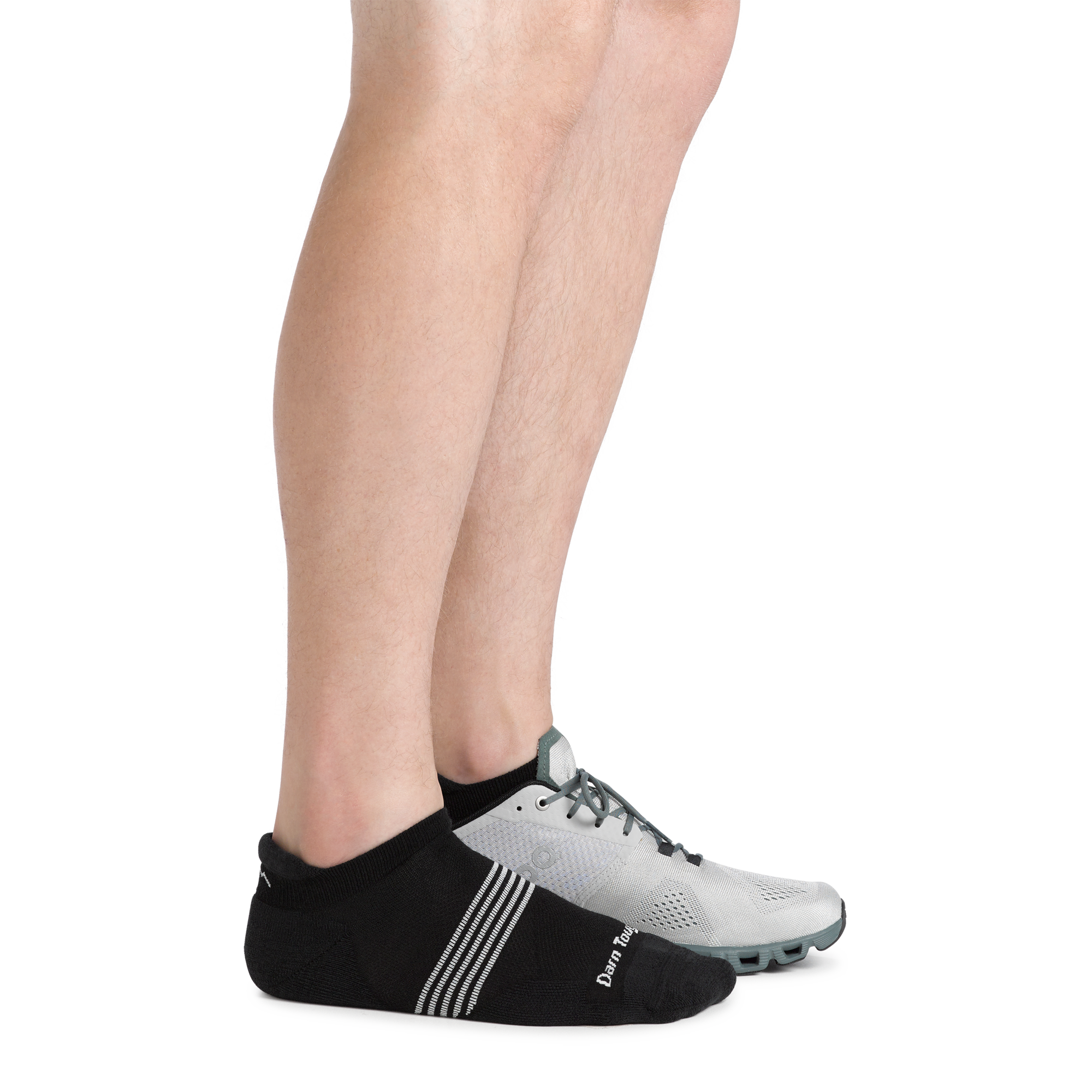 Side shot of model wearing the men's element no show tab running sock in Black with a gray sneaker on his left foot