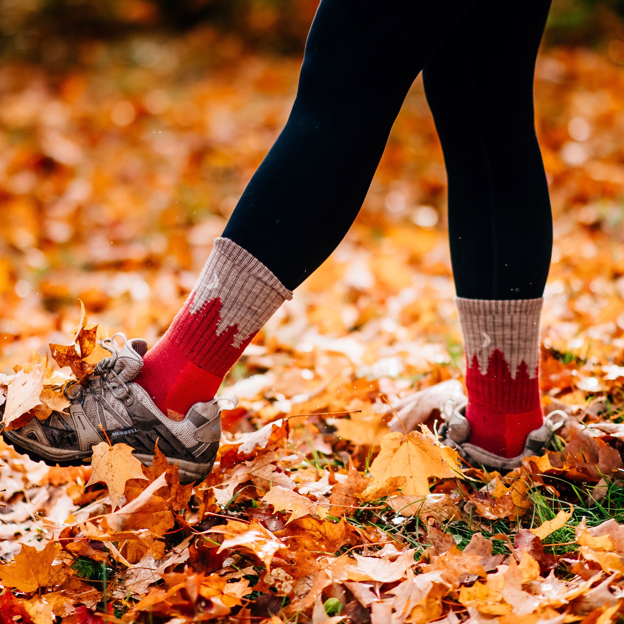 Woman wearing black leggings and kicking autumn leaves in women's treeline micro crew socks in cranberry