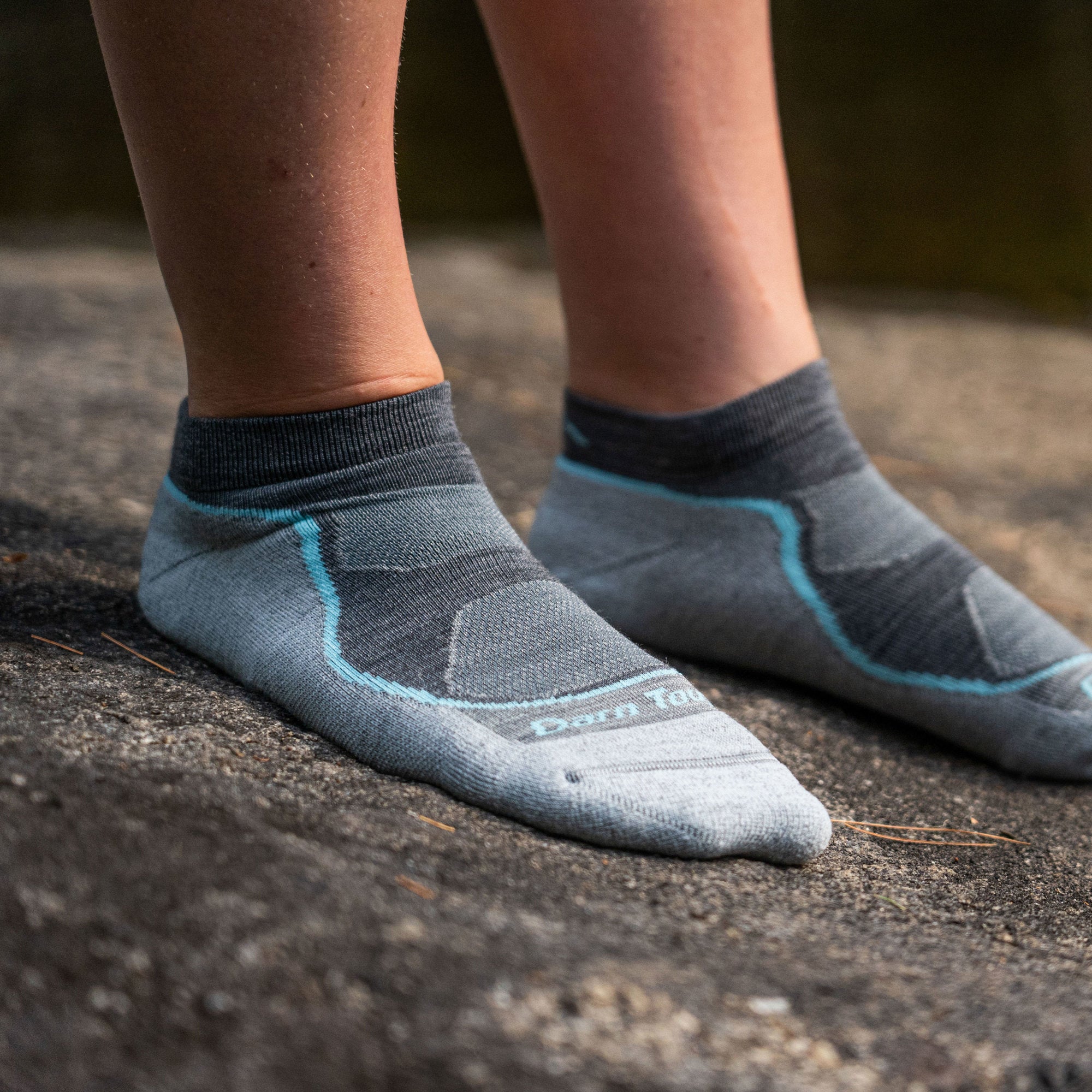 Close up image of a woman's feet, standing on a rock, wearing Women's Light Hiker No Show Lightweight Hiking Socks in Slate, Lifestyle Image