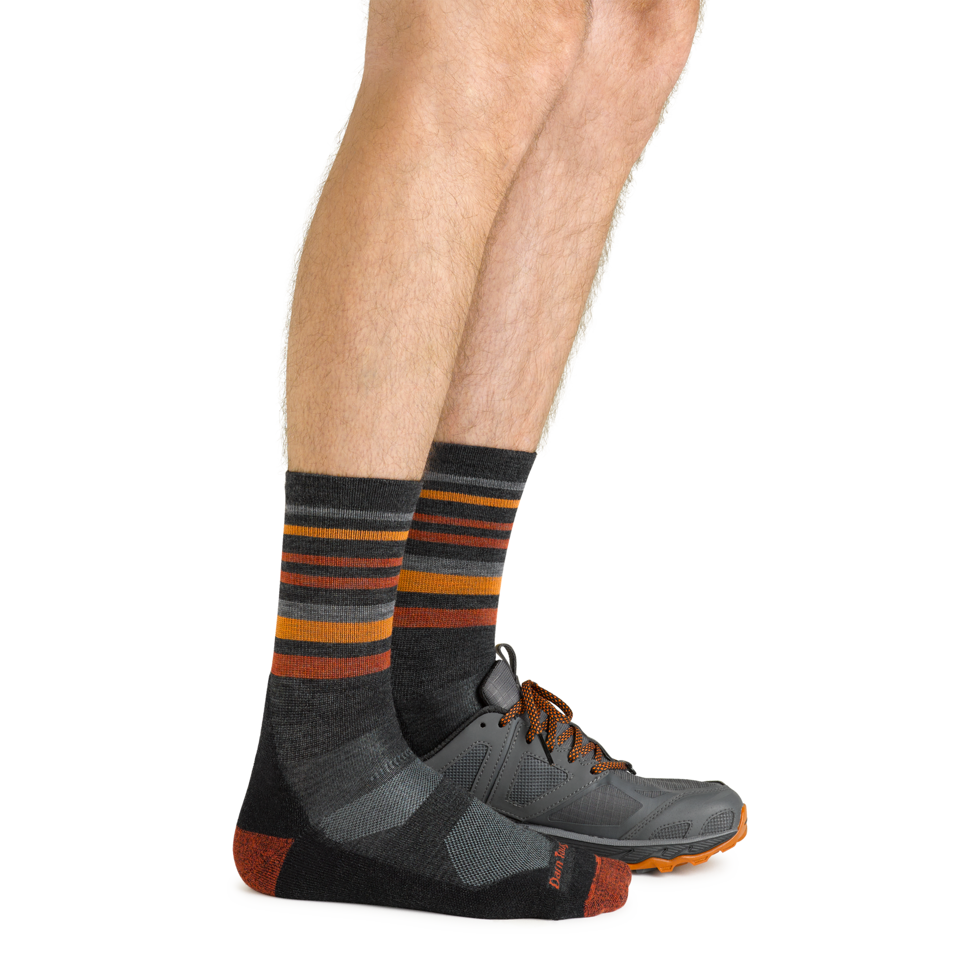 Side shot of model wearing the men's fastpack micro crew hiking socks in charcoal with a gray sneaker on his left foot