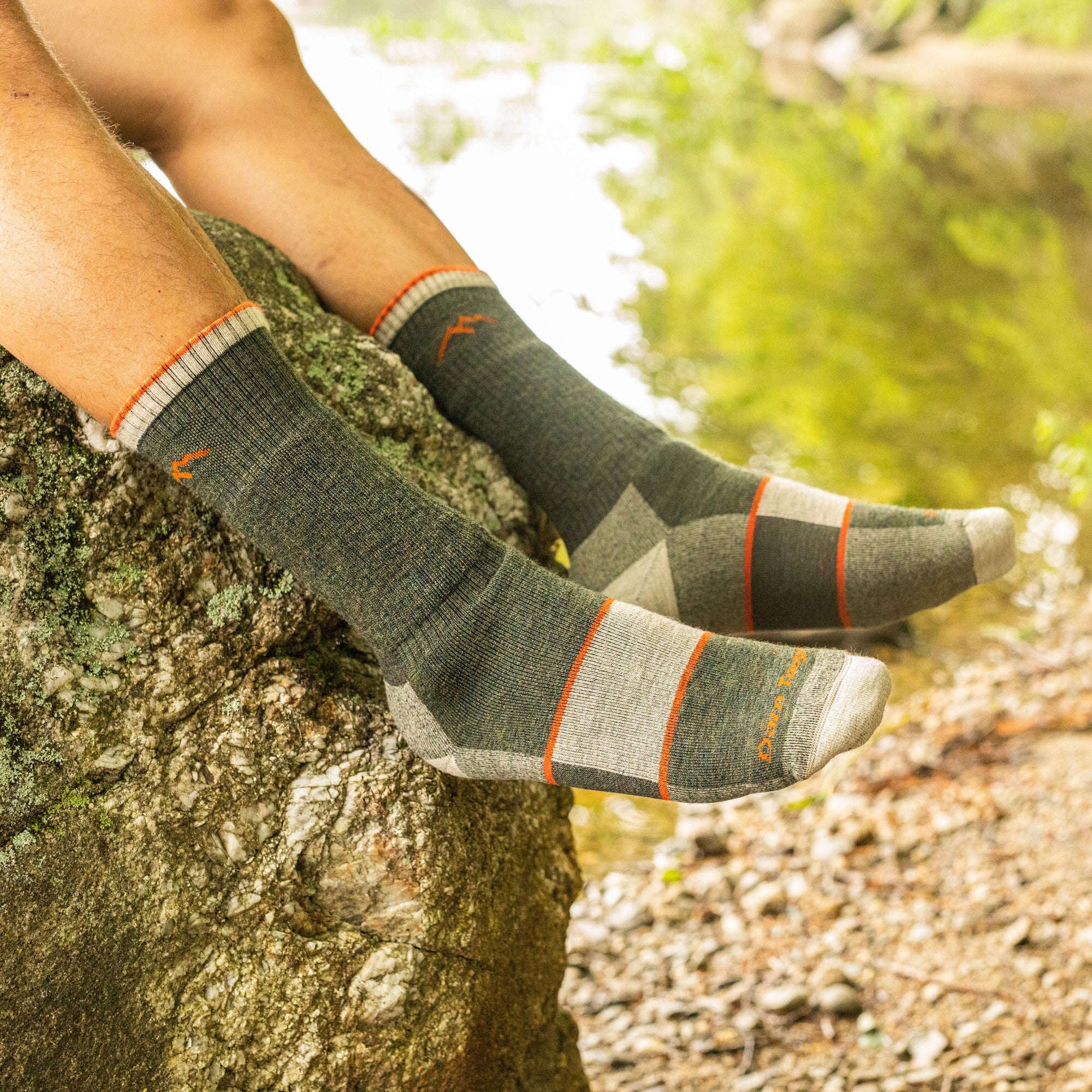 Close up shot of model sitting on the edge of a rock wearing the men's full cushion boot hiking sock in olive green