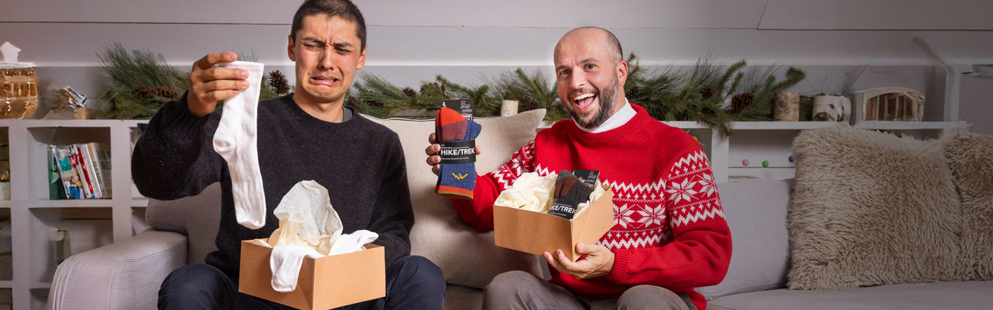 Two people opening their presents, one excited to get Darn Tough socks, the other sad he didn't