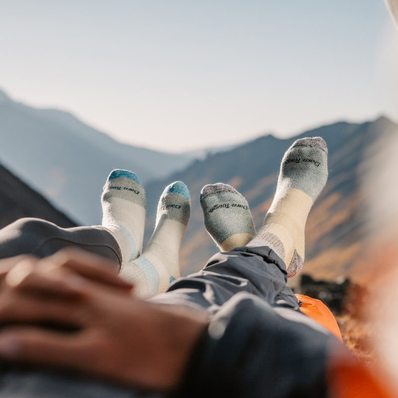 Two pairs of feet in warm merino socks, up on a mountain camping in a tent