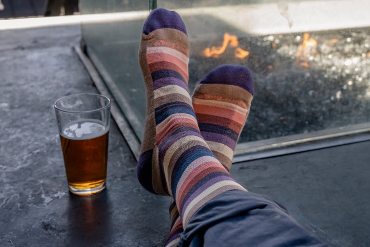 Shop lifestyle socks - Feet wearing striped socks, up by a fireplace with a drink